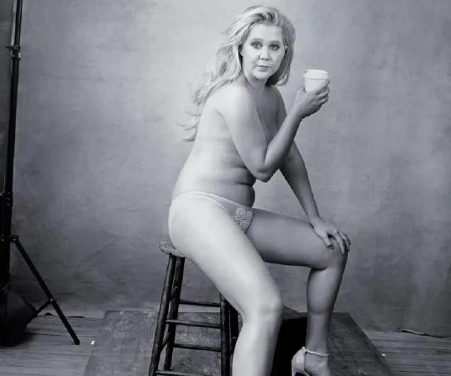 Nude Amy Schumer poses confidently on a stool holding a cup for the Pirelli Calendar.