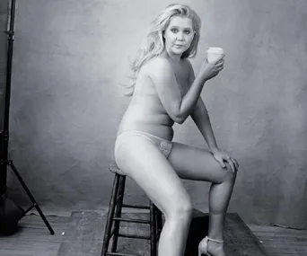 Nude Amy Schumer poses confidently on a stool holding a cup for the Pirelli Calendar.