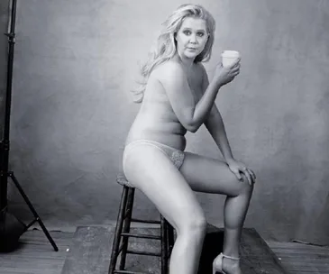 Nude Amy Schumer poses confidently on a stool holding a cup for the Pirelli Calendar.