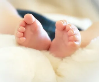 Close-up of a baby's feet resting on a soft, white blanket.