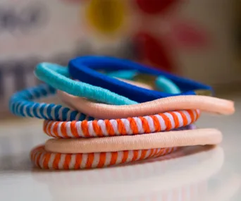 Colorful hair ties stacked on a reflective surface in close-up.