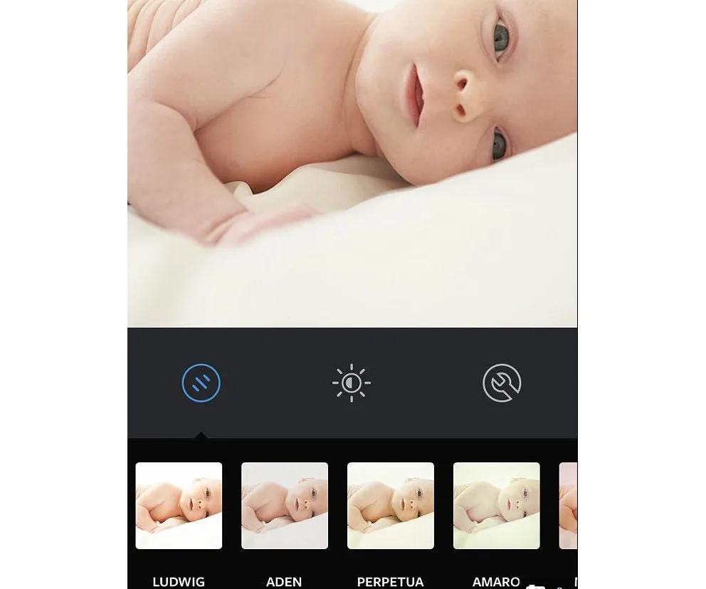 A baby lying on a bed with an Instagram filter menu below, featuring filters like Ludwig, Aden, and Perpetua.