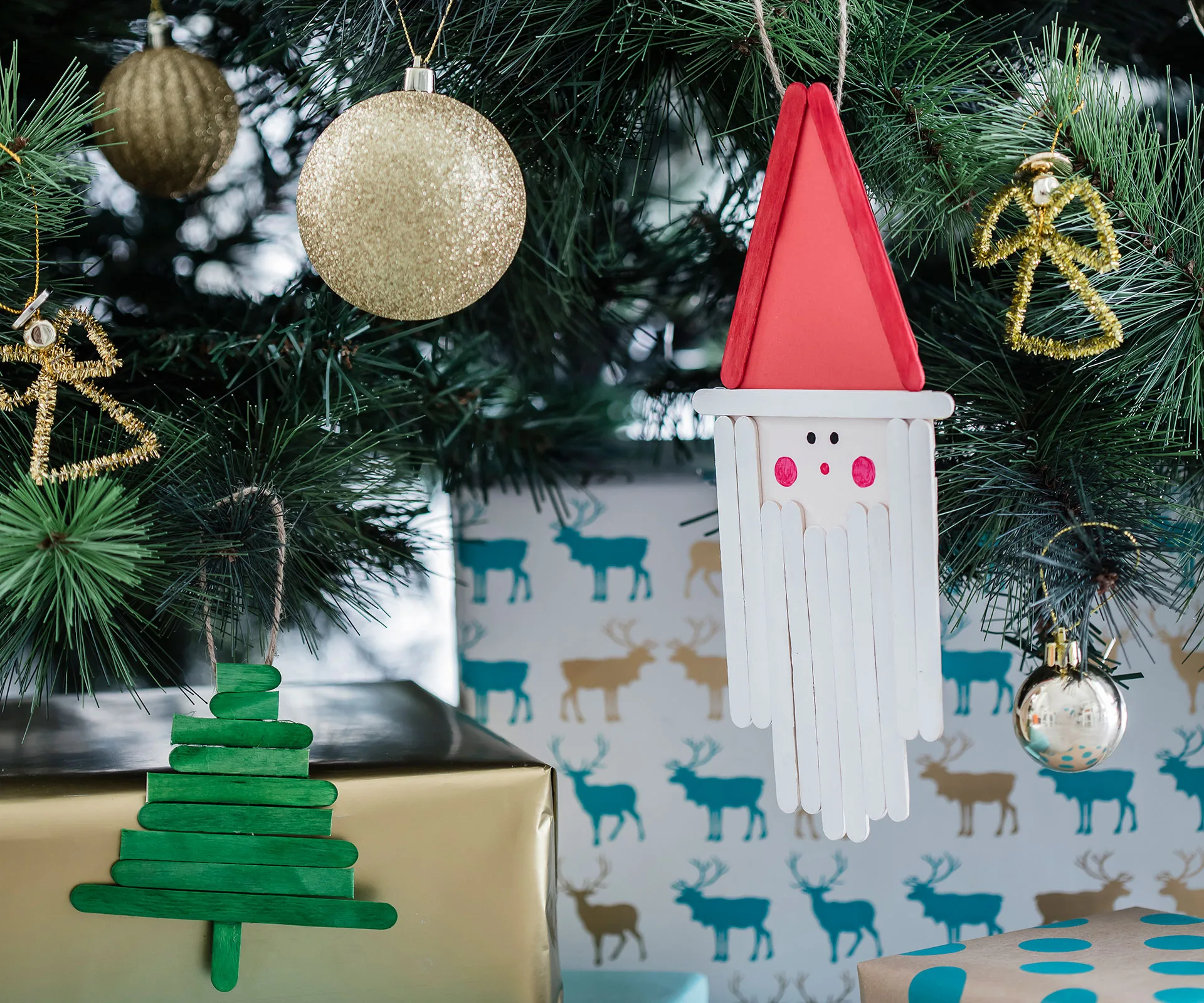 Christmas tree decorated with gold baubles, a Santa made of craft sticks, and a green tree ornament.