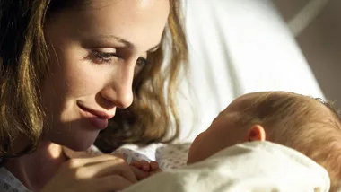 Mother lovingly gazes at her newborn baby, both in a hospital setting.