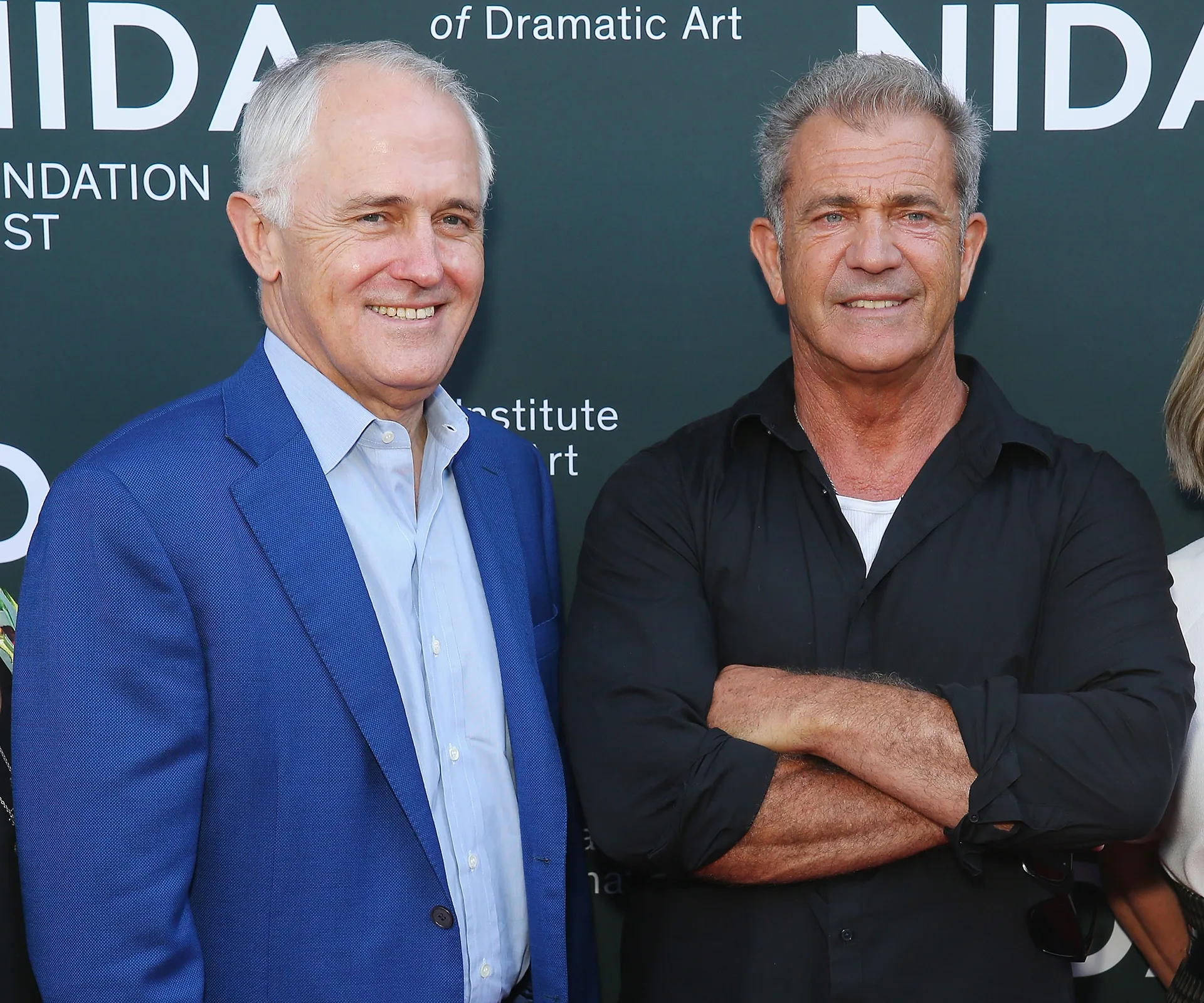 Two men smiling at the NIDA Arts School opening event backdrop.
