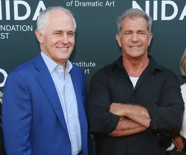 Two men smiling at the NIDA Arts School opening event backdrop.