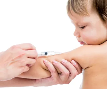 Child receiving vaccination in upper arm.