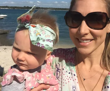"Mother and baby with headband at sunny beach."