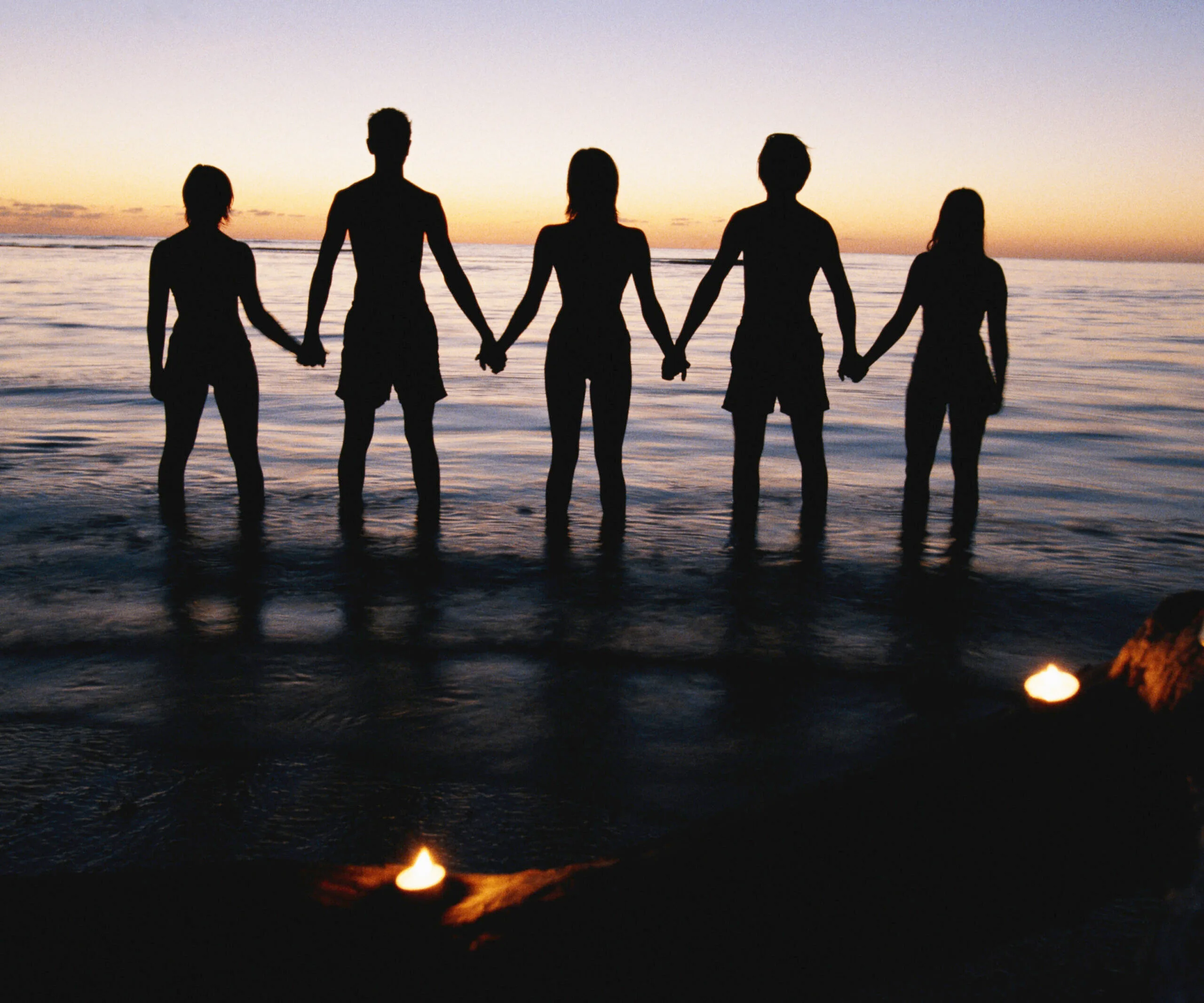 friends holding hands in the ocean