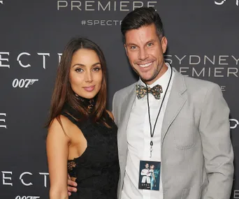 Couple posing at the "Spectre" Sydney premiere, with branded backdrop and event passes.