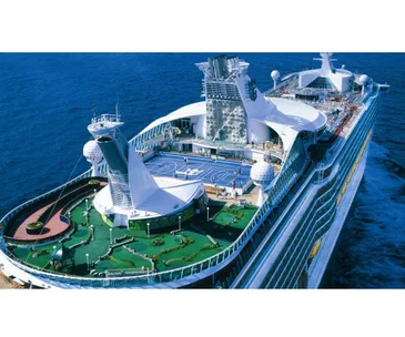 Aerial view of a large cruise ship at sea with sports courts and recreational areas on deck.