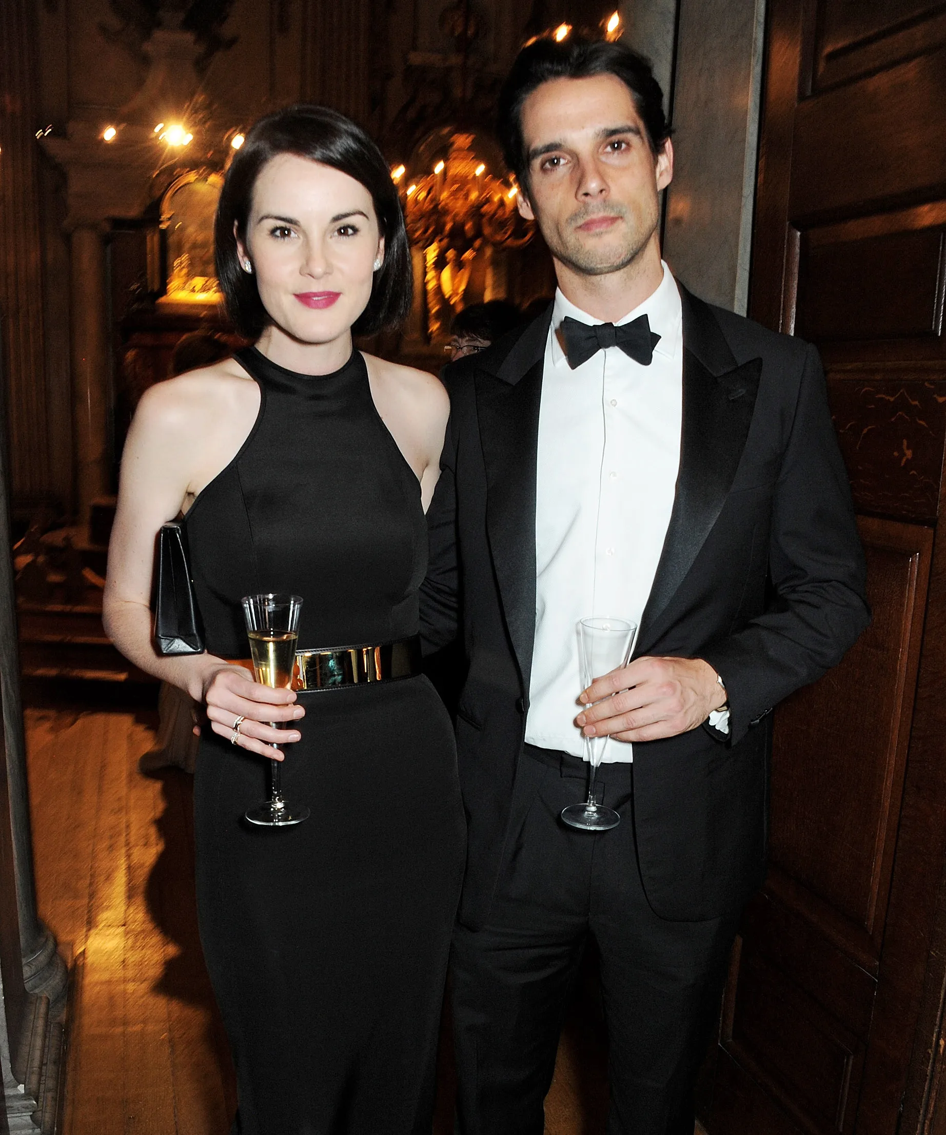 Two people in formal attire holding champagne glasses at an elegant event or gathering.