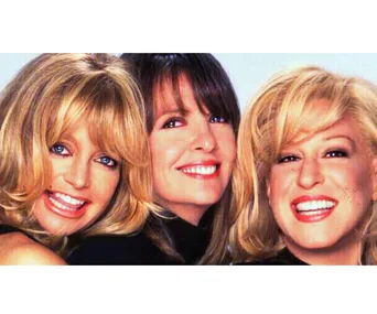 Three smiling women with blonde and brunette hair, posed closely together against a light background.