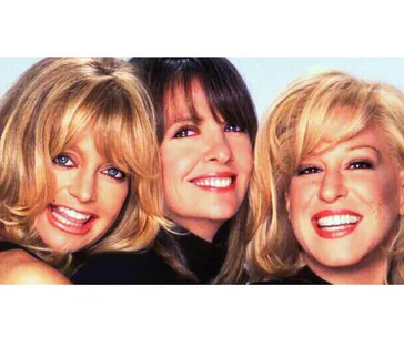 Three smiling women with blonde and brunette hair, posed closely together against a light background.
