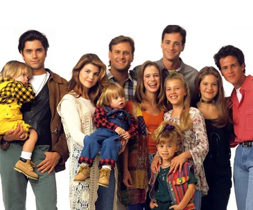 Cast of "Full House" gathered together in a group photo, smiling.