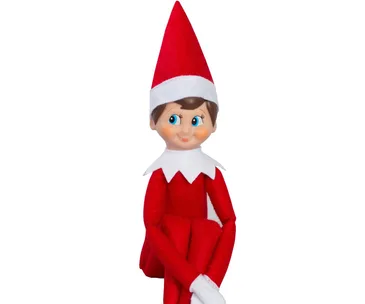 Elf on the Shelf doll with a red outfit and hat, sitting and smiling mischievously.