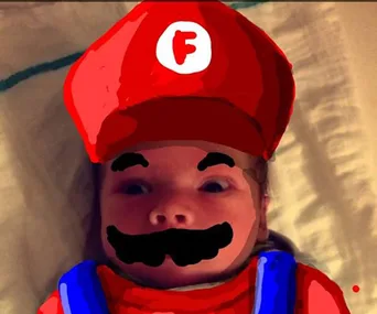 Baby with Mario-themed Snapchat doodle, in red cap with "F" logo, mustache, and blue overalls.