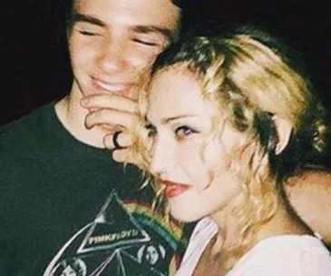 A woman with blonde hair poses closely with a young man wearing a Pink Floyd shirt, both smiling.