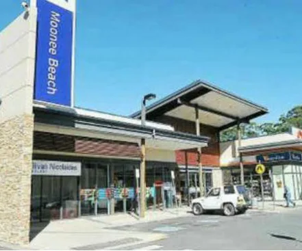 Moonee Beach shopping centre exterior with a small white car parked nearby and clear blue sky overhead.