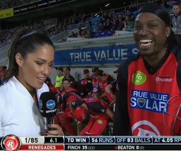 A cricket player with a "Renegades" jersey is interviewed by a reporter on a sports field.