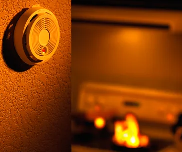 Smoke alarm on wall near stove with visible flames.