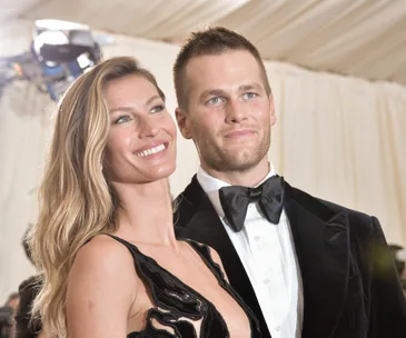 Couple at a formal event, woman in a black dress and man in a tuxedo, smiling.