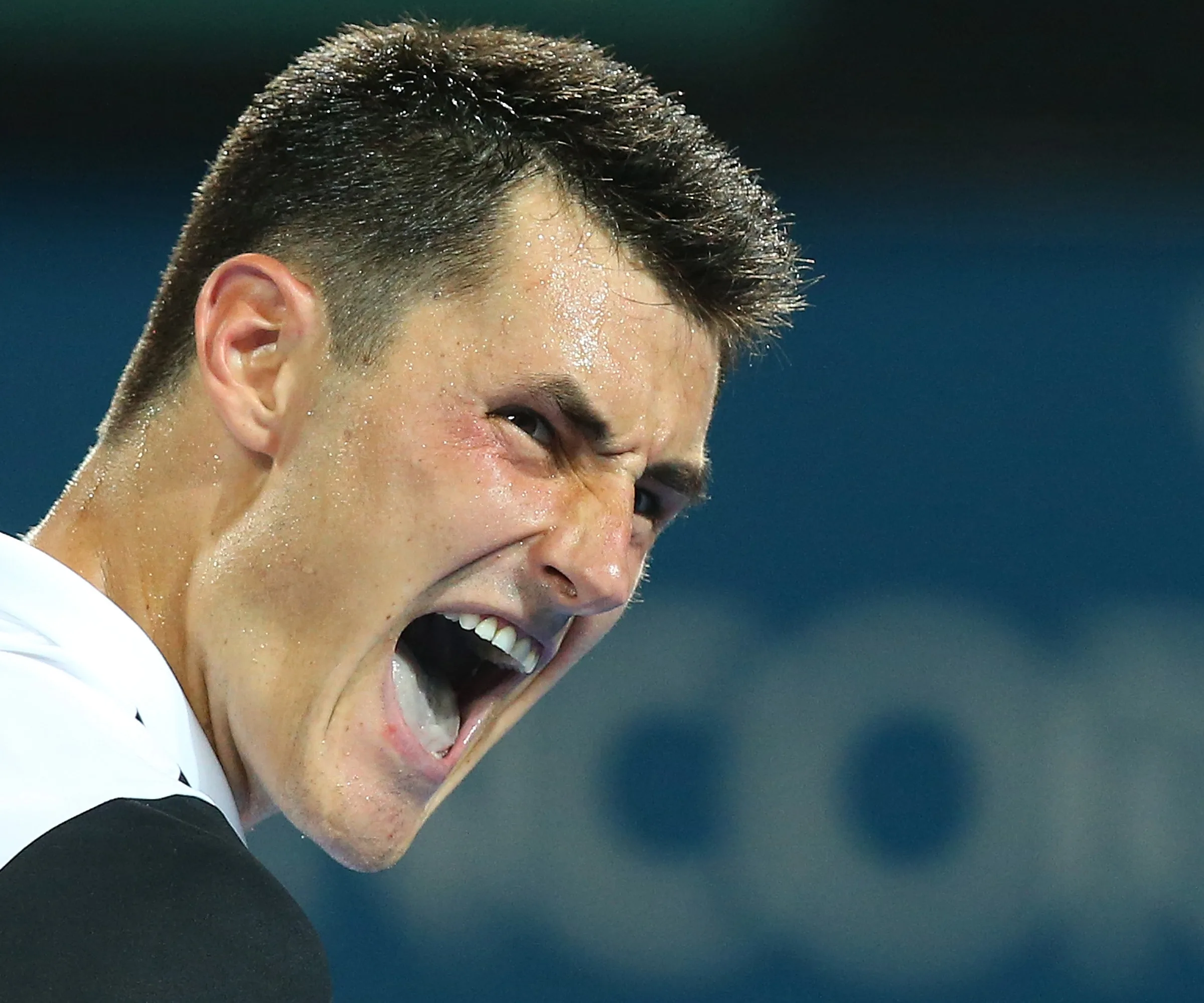 A tennis player intensely shouting during a match, showing frustration or determination.