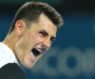A tennis player intensely shouting during a match, showing frustration or determination.