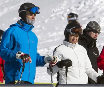 Group of three skiers in helmets and goggles standing in a snowy landscape, holding ski poles.