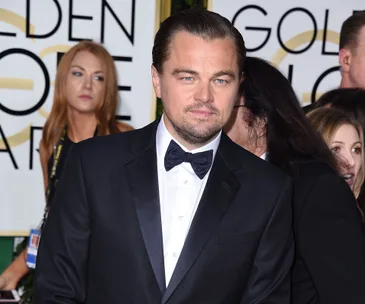 A man in a tuxedo at an event with a "Golden Globe" sign in the background.