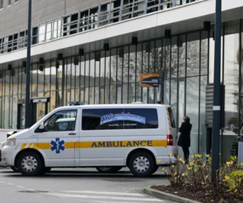 Ambulance parked outside a modern hospital building with a person standing nearby.