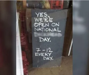 Sign reads: "Yes, we're open on National _______ Day. 7-12 every day." The blank word is obscured.