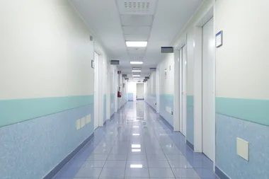 A clean hospital corridor with closed doors and fluorescent lighting.