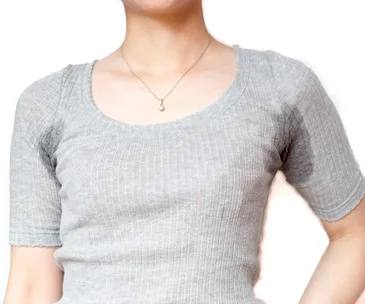 A person in a gray ribbed top with visible underarm sweat stains on a white background.