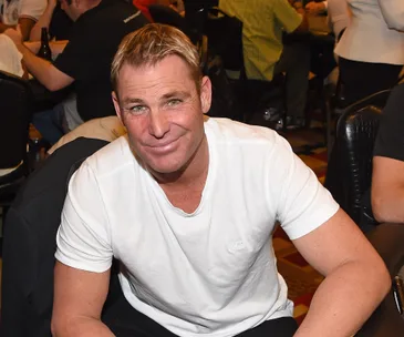 A person in a white t-shirt smiling at a table with others in the background.