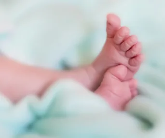 Close-up of a newborn baby's feet against a soft, light-colored background.