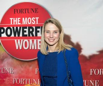 Smiling person in front of "FORTUNE The Most Powerful Women" sign, wearing a blue outfit.