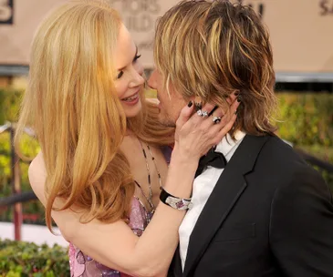 Red carpet moment with a couple embracing, both smiling warmly, exuding happiness and affection.
