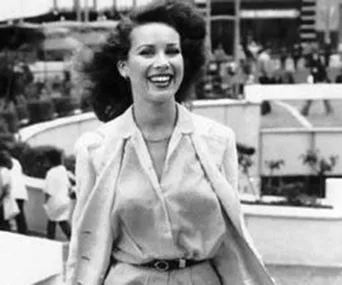 A smiling woman in business attire stands outdoors in a bustling urban setting.