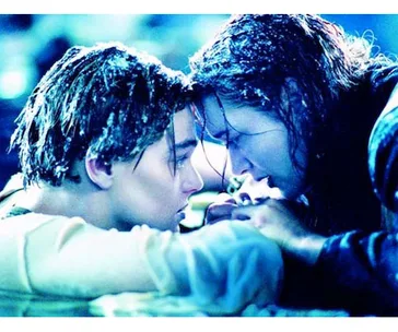 A scene from Titanic with two characters on a wooden plank in icy water, looking intensely into each other's eyes.