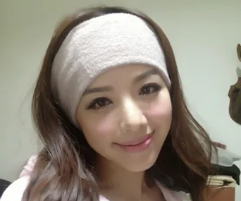 A woman with long hair and a headband smiles softly, posing indoors.