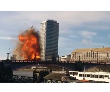 Explosion on a London bus for a film scene on a bridge, with a tall building in the background.