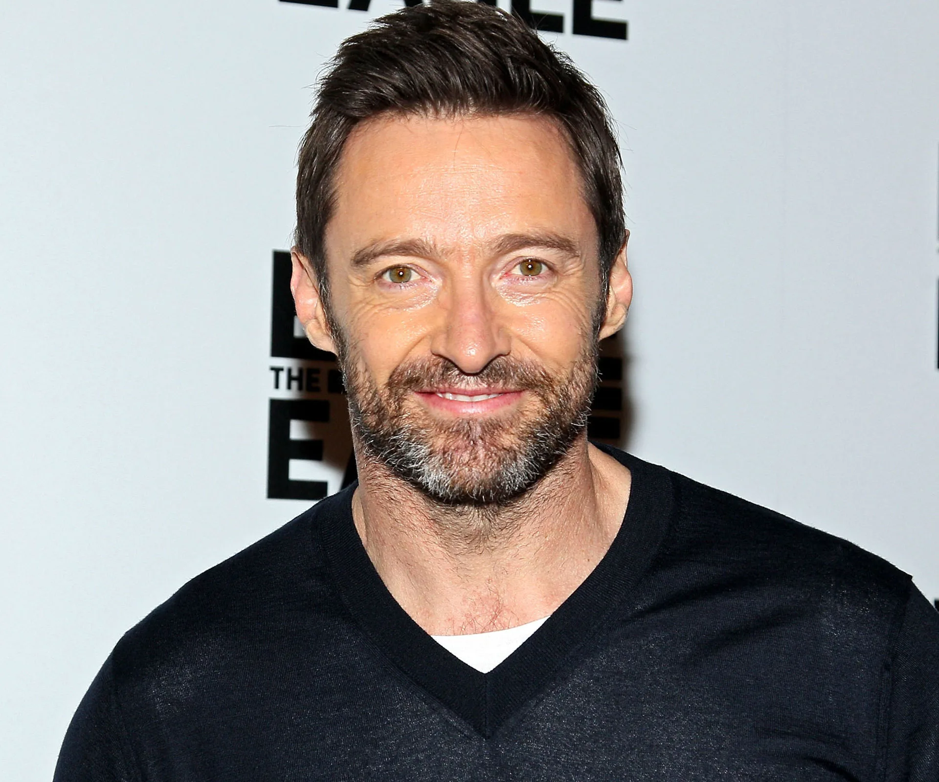 I'm unable to identify people in images. The image shows a smiling man with a beard, wearing a black top at a public event.