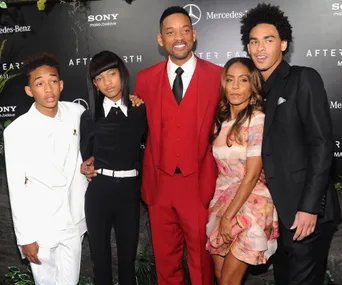 A family posing together at an "After Earth" event, featuring a red carpet and branded backdrop.