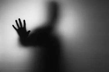 "Silhouette of a hand against a blurred, ghostly background."