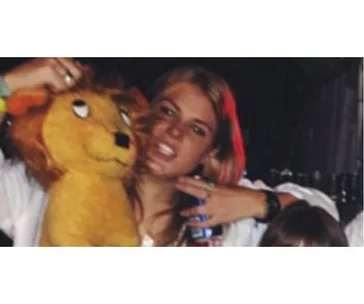 A person holding a plush lion toy in a celebratory setting with friends.