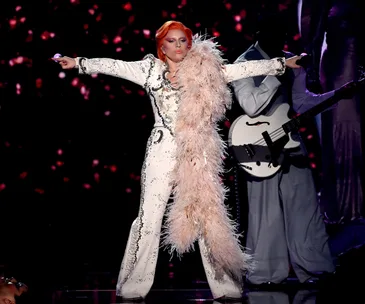 Lady Gaga performs David Bowie tribute at 2016 Grammys, wearing embellished suit with pink feather boa.
