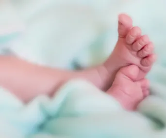 "Close-up of baby feet wrapped in a soft, light green blanket, creating a serene and tender atmosphere."