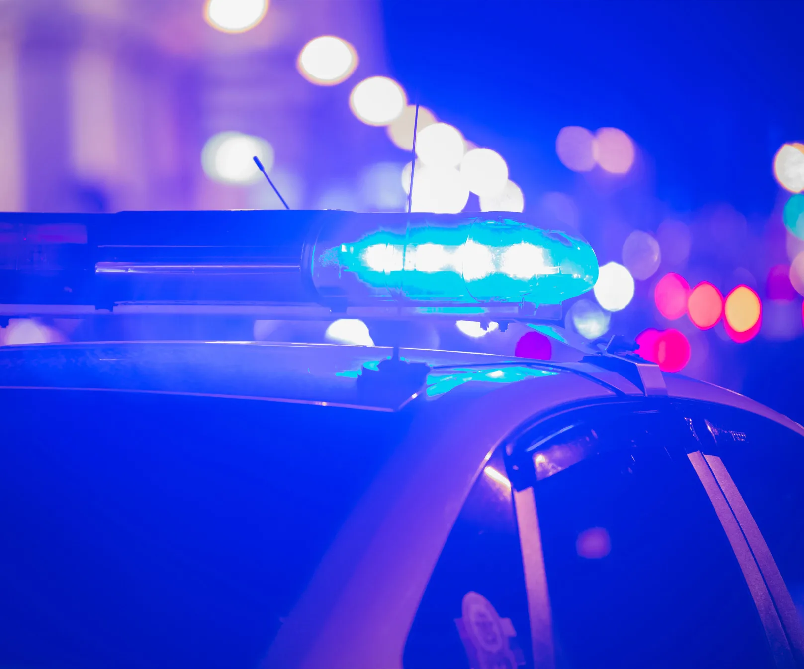Police car with blue flashing lights in a city at night.