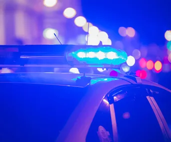 Police car with blue flashing lights in a city at night.